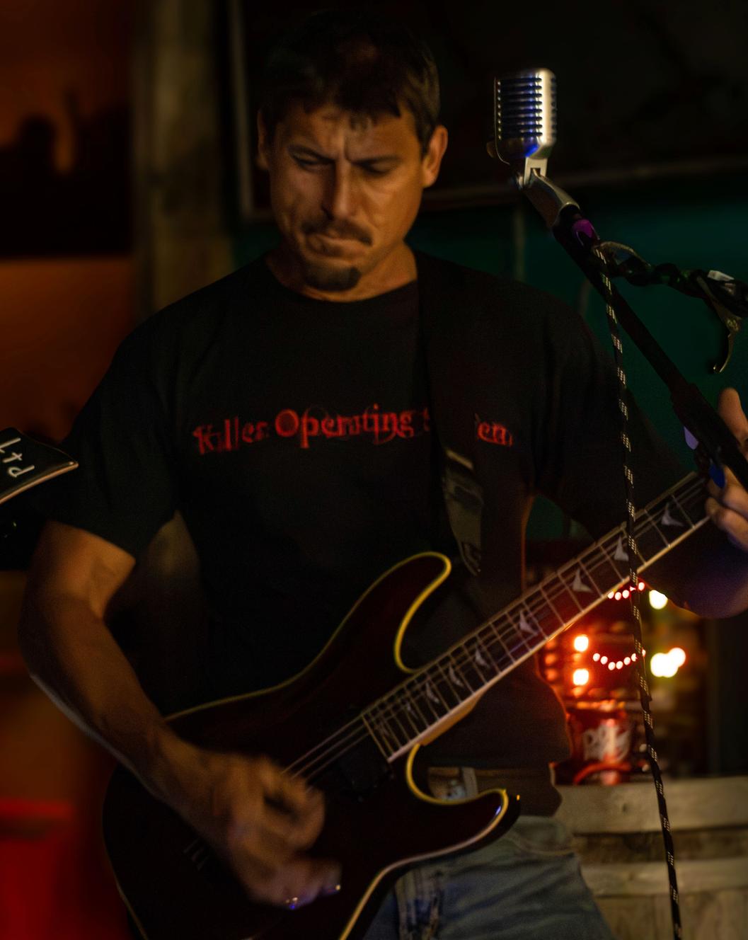 Jason ripping a lead guitar solo under colored lights